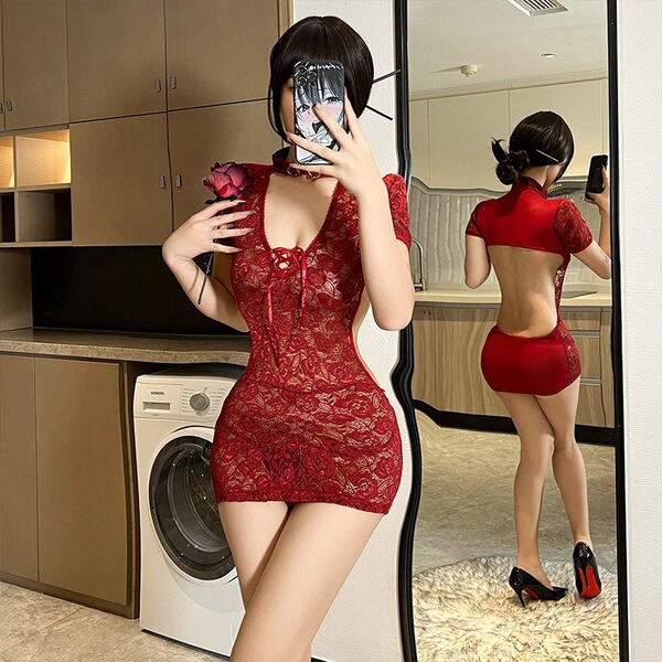 Woman in red lace bodysuit with sheer panels and mini dress silhouette, posing in front of mirror holding rose and phone.