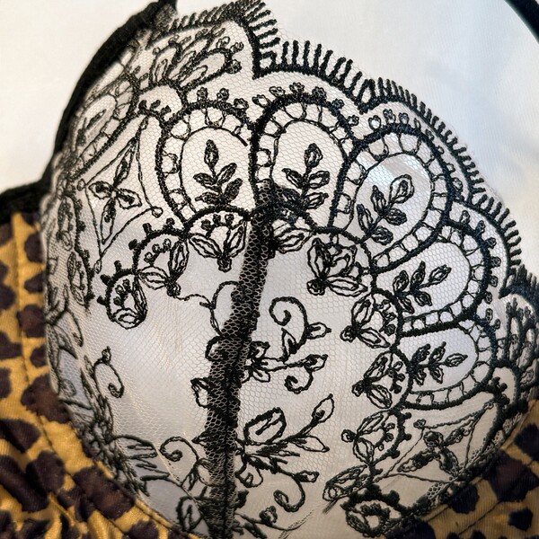 Close-up of sheer mesh bra with black floral embroidery over leopard print lining.