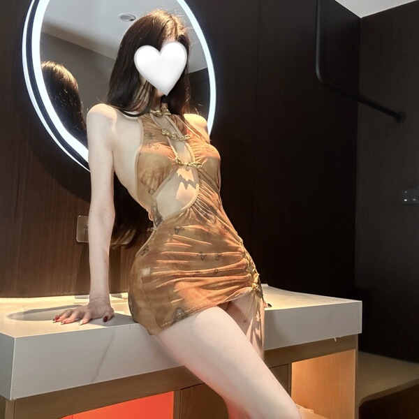 Woman wearing sheer vintage-inspired cheongsam sleepwear with cut-outs, high slit, and chest detailing in warm-toned lingerie...