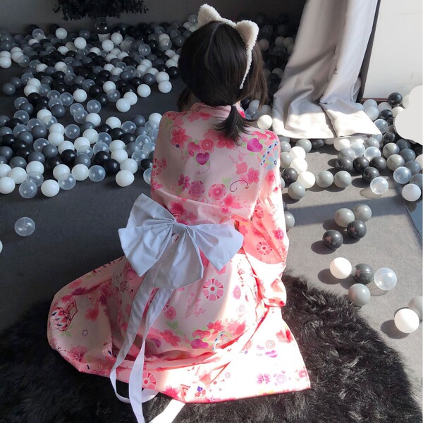 A person wearing a pink floral japanese-style kimono with cat ears sits among colorful balls, creating a playful scene ideal ...