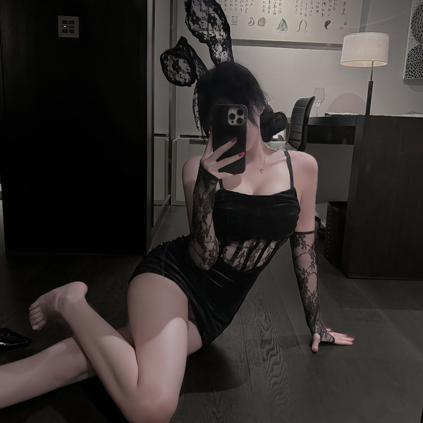 A woman poses in a black bodycon dress with lace-up details and sheer sleeves, capturing herself in a mirror. the outfit feat...