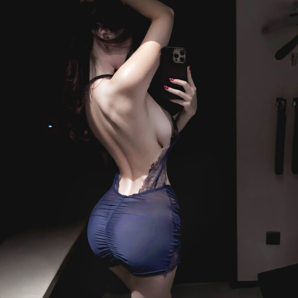 Woman in mannyqing lace necktie lingerie set, sheer cross-back bra and panty set, taking a mirror selfie.