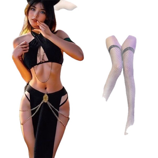 Woman wearing black cutout halter bodysuit with gold chains and fishnet stockings, styled as a catwoman-inspired lingerie set...