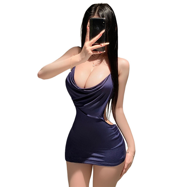 A woman poses with her phone, wearing a navy blue manyan dress featuring a plunging neckline and halter straps, creating a se...