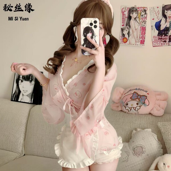 A woman poses with a phone, wearing a delicate pink kimono-style maid sleepwear dress featuring floral patterns. the outfit i...