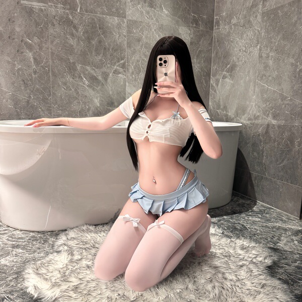 Woman in bathroom wearing night night sexy lingerie set: white crop top, blue pleated mini skirt, thigh-highs — pure yet te...