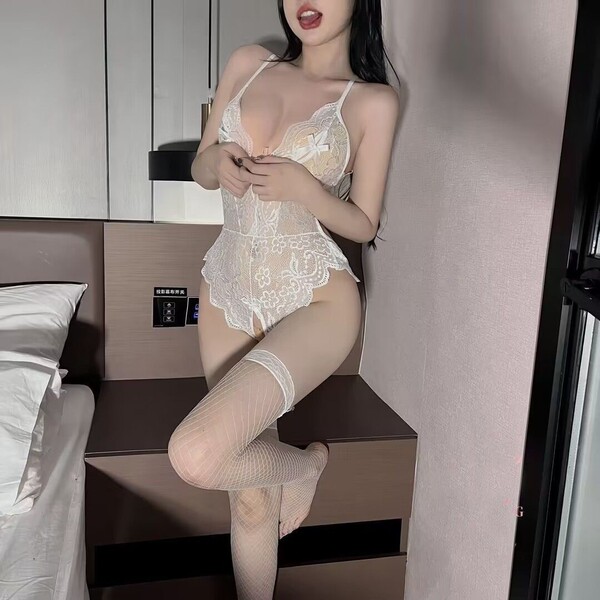 Woman wearing white lace passion lingerie set with cut-outs and open-crotch design, paired with sheer thigh-high stockings.