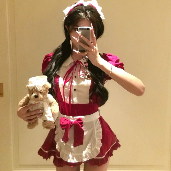 A person wearing a red and white maid costume holding a teddy bear, perfect for cosplay and roleplay fun.
