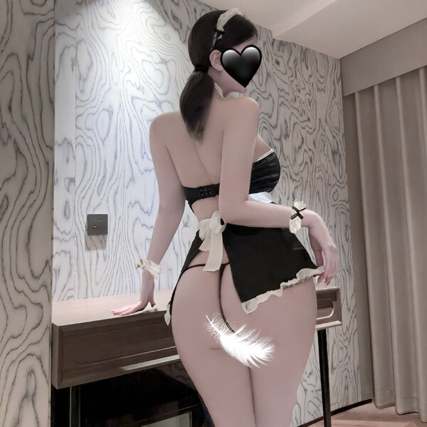 Woman wearing a black and white plus size maid costume with open-crotch design, featuring lace trim and bow accents.