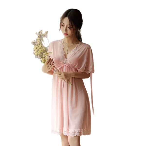 A woman holds a bouquet while wearing a sheer pink plus-size sleepwear set, featuring delicate lace details and soft fabric f...