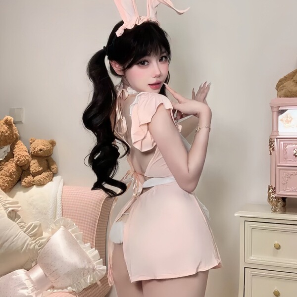 Woman modeling pink lace bunny girl costume with ruffled trim and sheer mesh details, featuring bunny ears headband and playf...