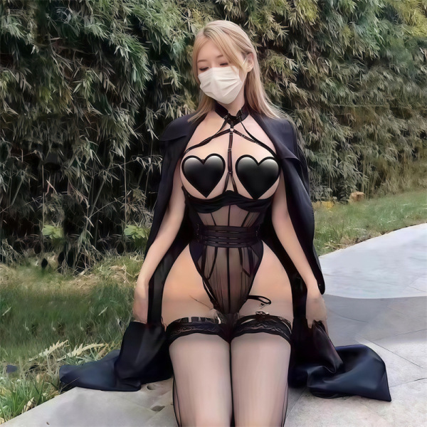 Woman in black plus size sexy lingerie set with heart-shaped bra and sheer thong, posing outdoors.