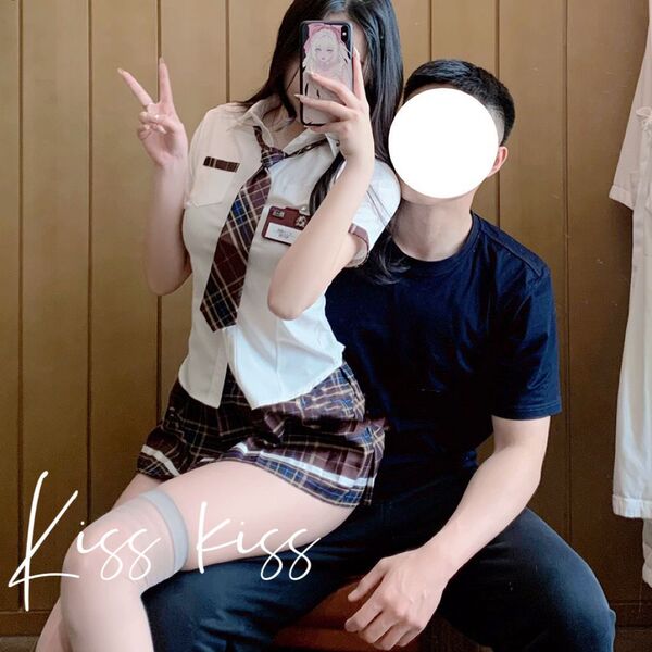 A woman in a schoolgirl maid outfit poses with a man, wearing a police uniform-themed skirt and top. the image features playf...
