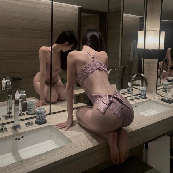 Woman in pure & alluring lace lingerie set – flirty sensual babydoll with ruffled hem, kneeling on bathroom counter.