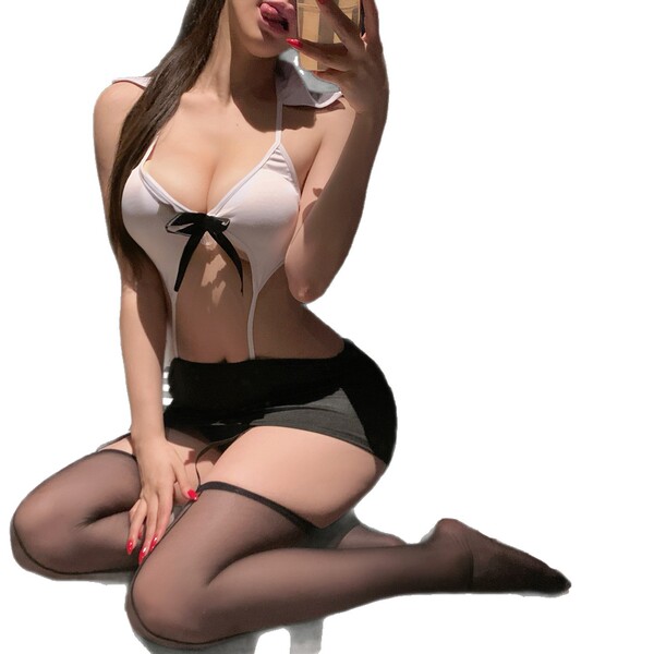 Woman in white lingerie set with black bow, sheer stockings, and garter belt posing seductively.