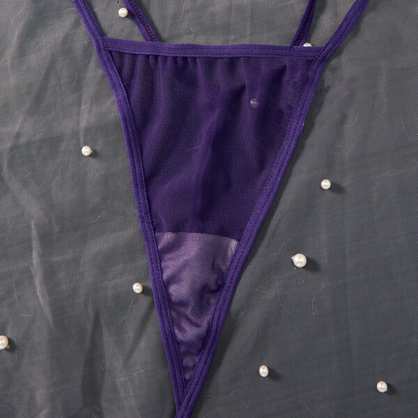 Purple velvet thong from pure & playful bunny girl lingerie set, displayed on dark fabric with scattered pearls.
