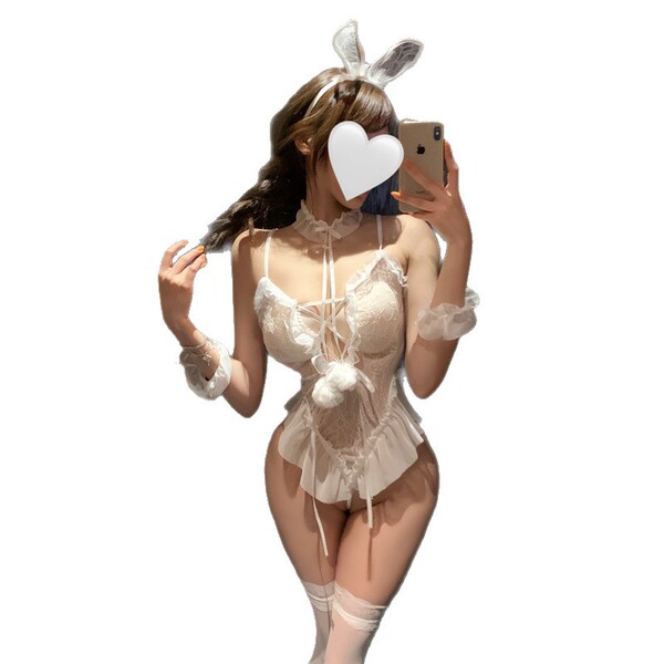 Woman in white bunny lingerie set with ears, lace bodysuit, and thigh-high stockings taking a mirror selfie.