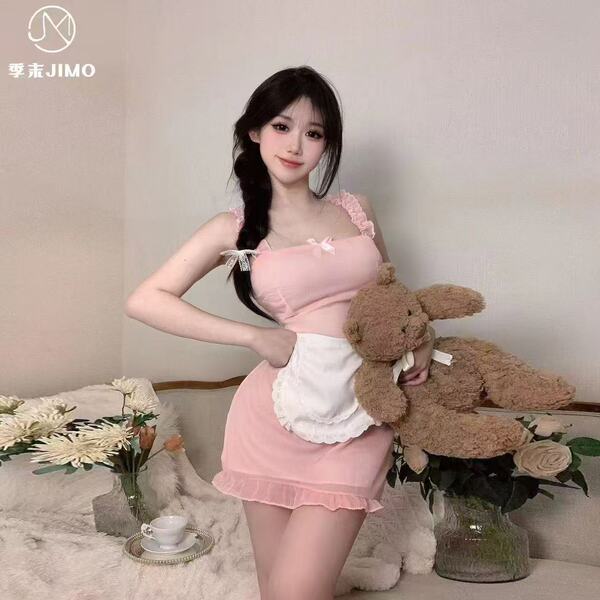 A woman poses with a teddy bear, wearing a pink sheer sleepwear set featuring a nurse apron design. the outfit combines playf...