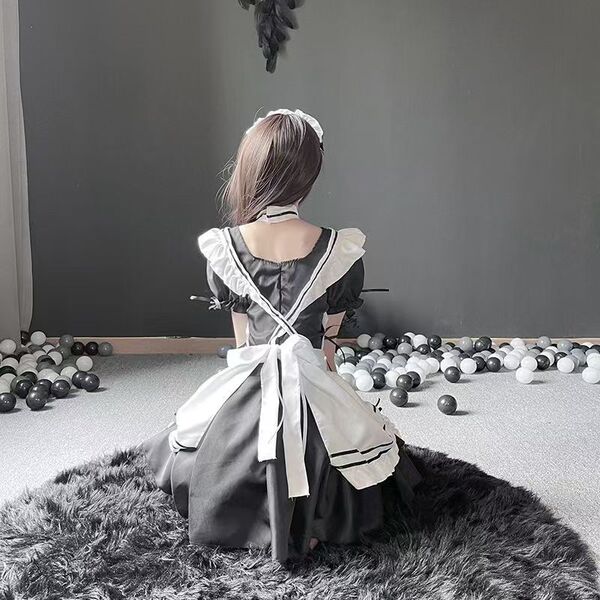 A girl wearing a black and white maid costume sits on a rug surrounded by balls, showcasing a cute japanese schoolgirl outfit...