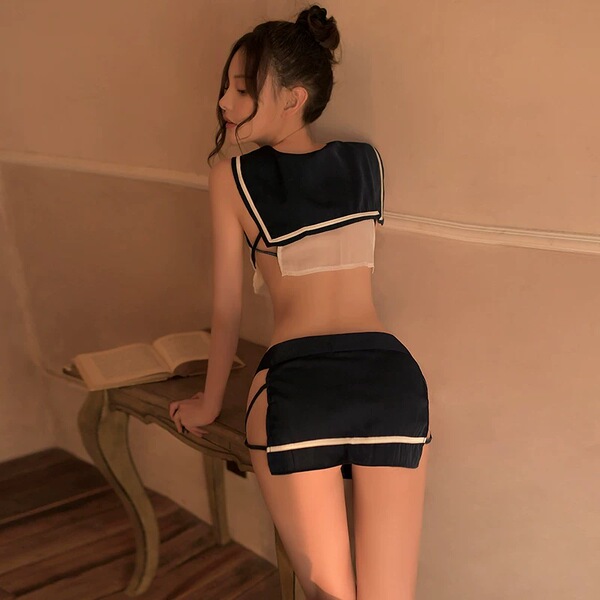 A woman stands against a wall wearing a black lace-trimmed camisole dress paired with sheer stockings and matching nightwear ...