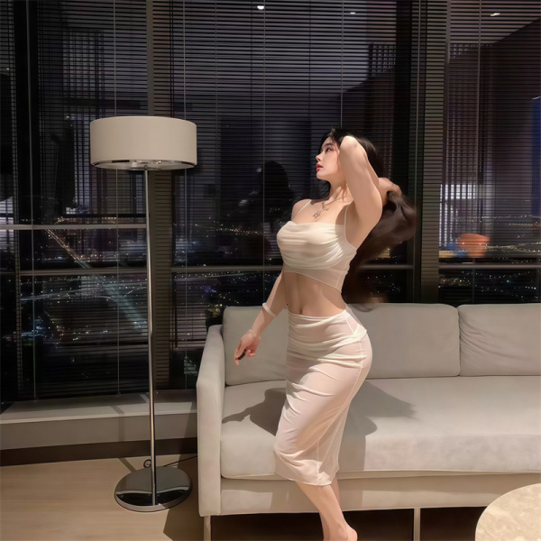 Woman in sheer lace bodysuit dress, elegant sleepwear set, posing by window at night.