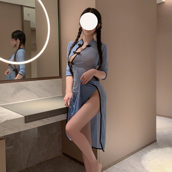 A woman poses in a bathroom wearing a light blue lace cheongsam lingerie set, featuring a high slit and elegant design, perfe...