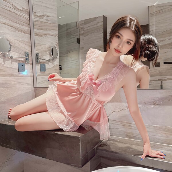 Woman in pink lace sleep dress with satin blend, adjustable straps, posing elegantly on bathroom counter.
