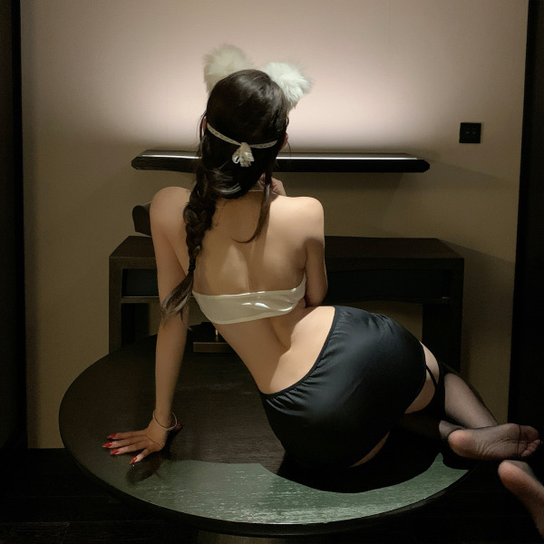 Woman in pure & seductive lingerie set, featuring open-crotch design and secretary-style top, posing on table.