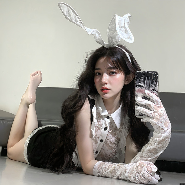 A woman poses with bunny ears and lace gloves, wearing a white blouse and black skirt combo, embodying a playful yet elegant ...