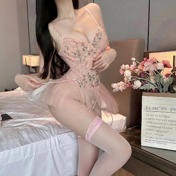 Woman wearing pink embroidered lace bodysuit with sheer mesh, adjustable waist tie, and open-crotch design.