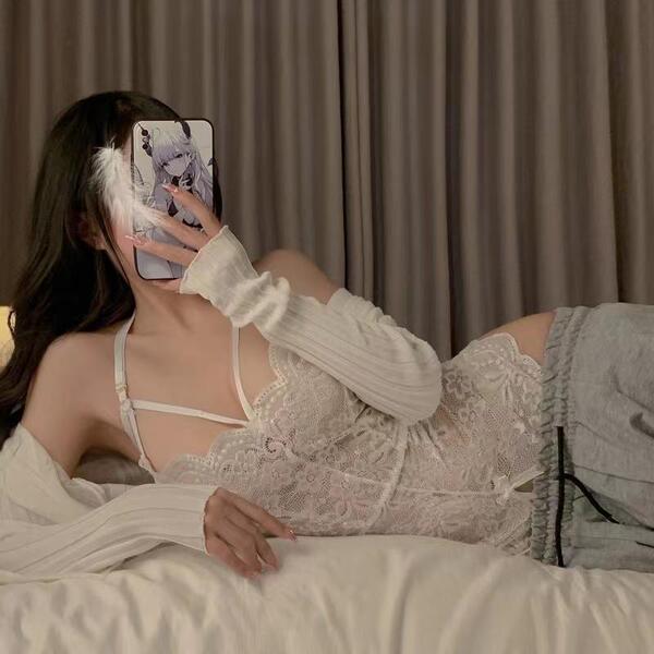 Woman lounging in white pure temptation lace bodysuit, sheer romantic lingerie with off-shoulder sleeves and matching shorts.