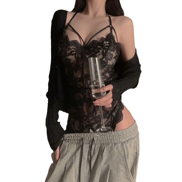 Woman wearing black lace bodysuit with sheer panels, holding wine glass, styled for romantic bedroom wear.