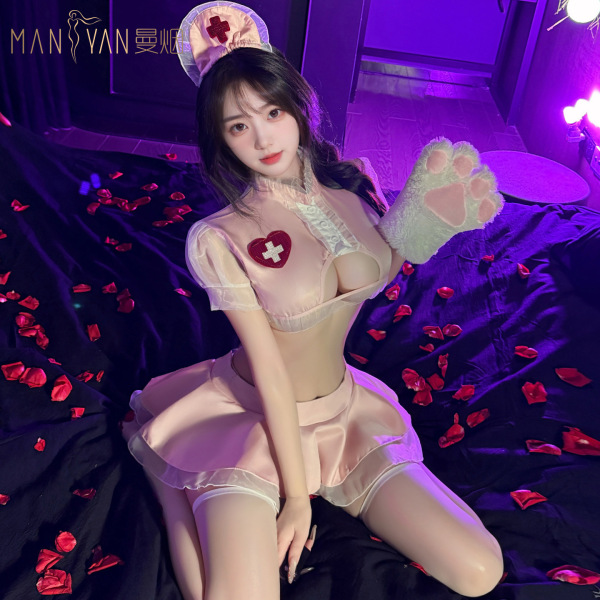 Woman in pink pure temptation nurse costume with lace, petticoat skirt, paw glove, and rose petals on dark bed.