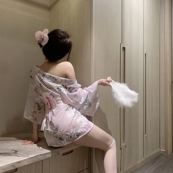 A woman sits on a counter wearing a delicate pink japanese-inspired kimono lingerie set, featuring floral patterns and soft f...