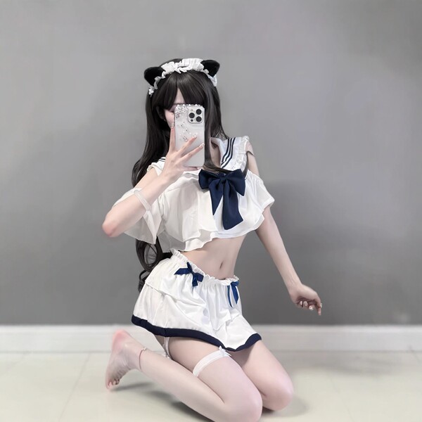 A woman poses with a smartphone, wearing a navy collar bow skirt from the pure & tempting jk uniform set. the outfit features...