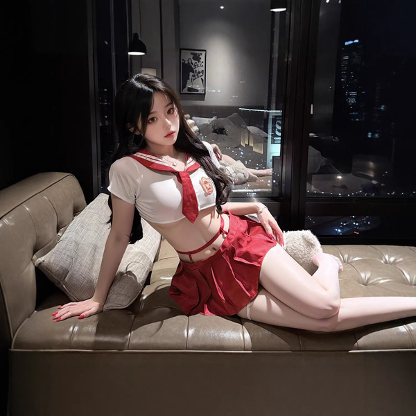 A stylish young woman poses on a leather couch wearing a vibrant red and white sailor-style skirt outfit, perfect for cosplay...