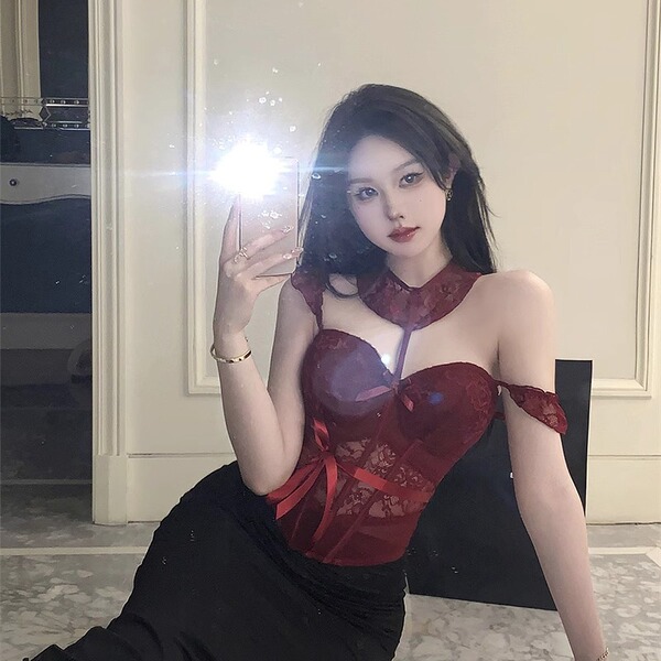 A woman poses with a mirror, wearing a red lace push-up corset vest set paired with black bottoms. the design features sheer ...