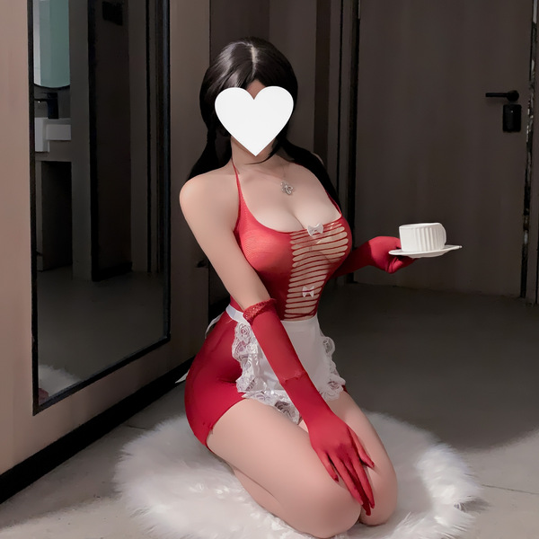 A woman poses in a red sheer mesh costume with lace details, holding a cup. the outfit features a ripped design and long glov...