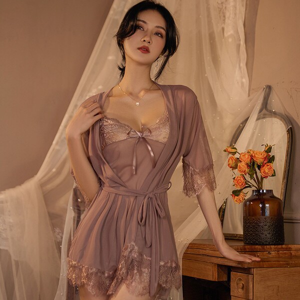 Woman wearing qing lian yi plus size lingerie set with lace-trimmed slip dress and matching robe, posed in soft bedroom setti...