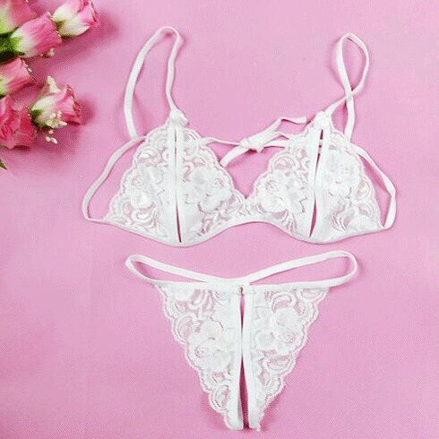 White lace thong bra set with sheer open-crotch design, delicate floral embroidery, adjustable straps, romantic pink backgrou...