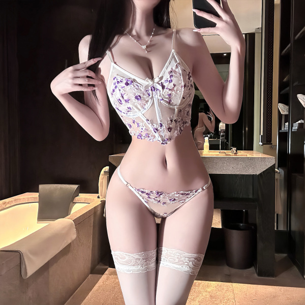 Woman wearing qingshe lace lingerie set with floral embroidery, push-up bra and thong, in elegant bathroom setting.