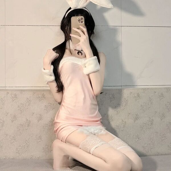 A person wearing a pink rabbit girl costume set, featuring a fluffy tail, plush bunny gloves, and lace stockings, posing for ...