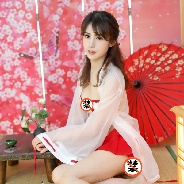 A woman poses elegantly in a shrine maiden kimono-style outfit, featuring a sheer robe over a red bra and pleated skirt, set ...
