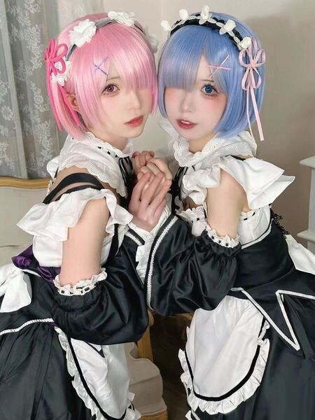Two cosplayers dressed as ram and rem from re:zero, wearing maid outfits in lolita style anime cosplay dress.