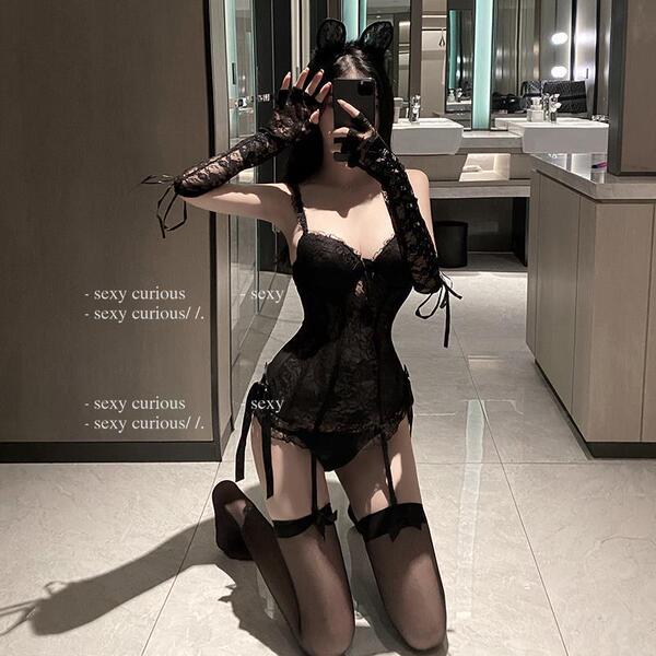 Woman kneeling in black lace lingerie set with sheer mesh bodysuit, garter stockings, and cat ears.