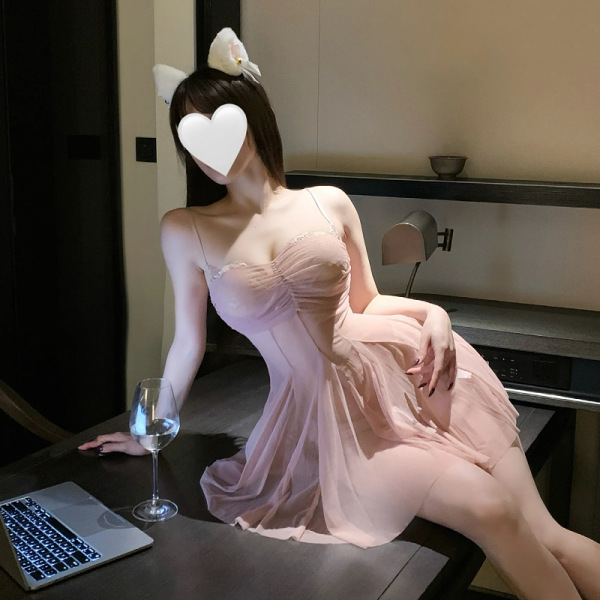 Woman in pink seductive lace mesh slip dress set posing elegantly at a table with wine glass and laptop.