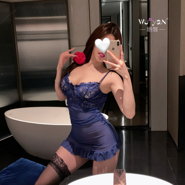 Woman in a blue lace lingerie set with a rose, posing seductively in a modern bathroom setting.