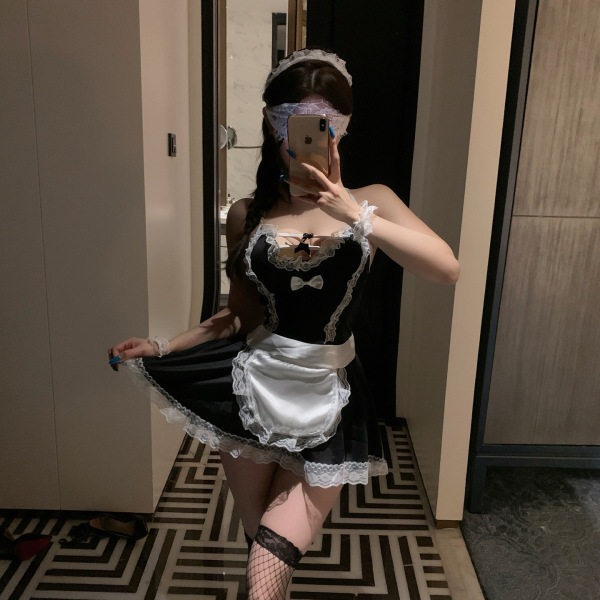 Woman in a seductive maid costume lingerie set, featuring a black dress with white lace trim and apron, paired with fishnet s...