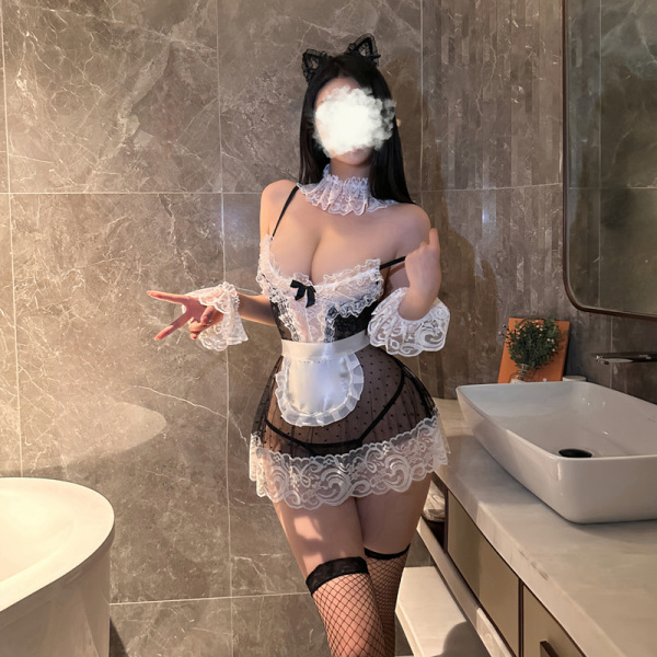 Woman wearing seductive maid costume set with lace, tulle dress, apron, cat ears headband, and fishnet stockings in bathroom.