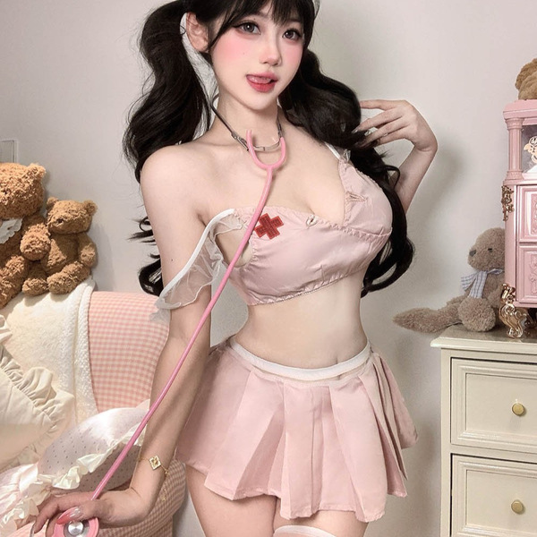 Woman wearing pink seductive nurse costume set with bow backless design, holding stethoscope in cozy room setting.